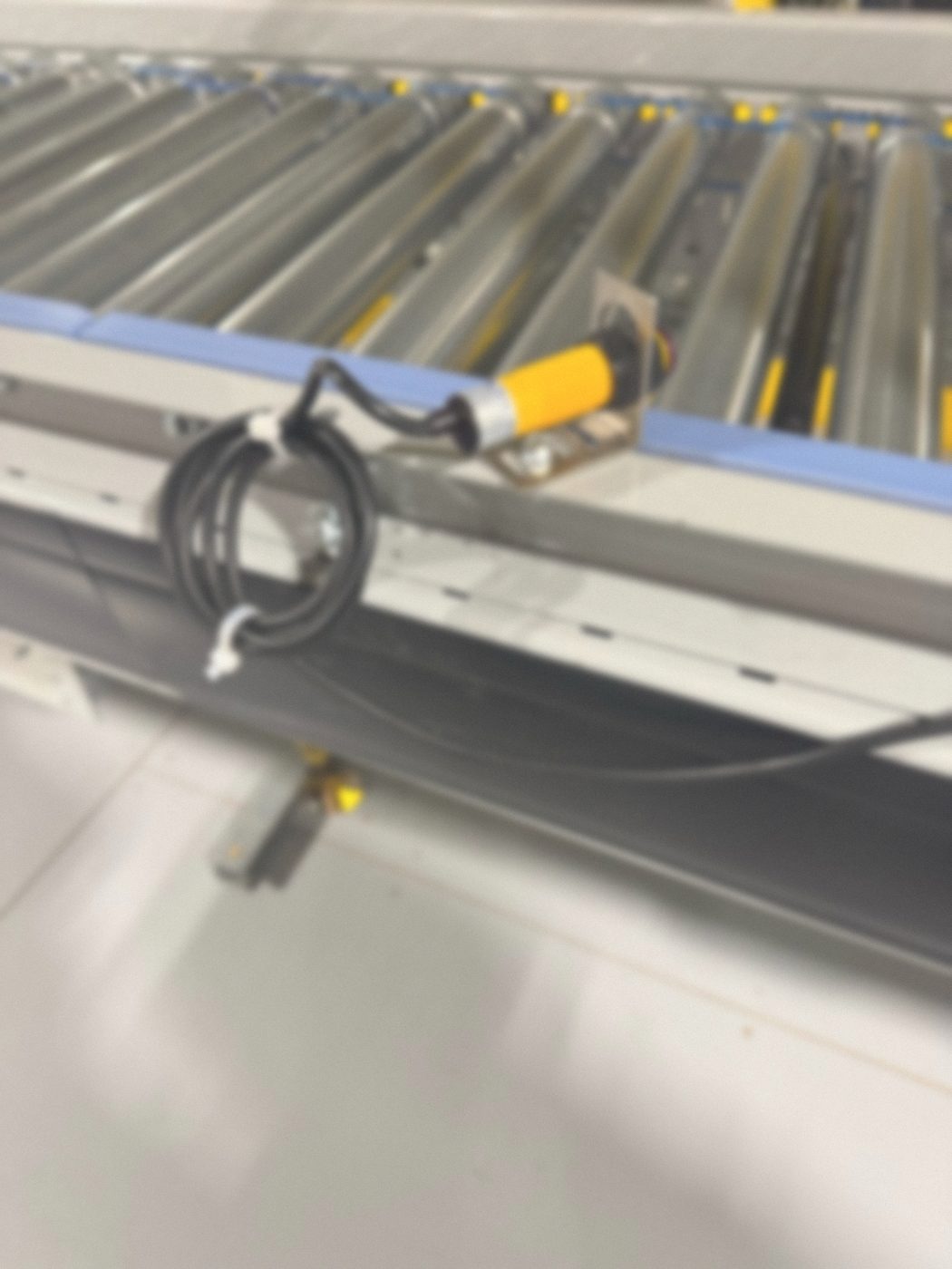 Photoelectric sensor on a proper mounting bracket with its cable secured on a conveyor